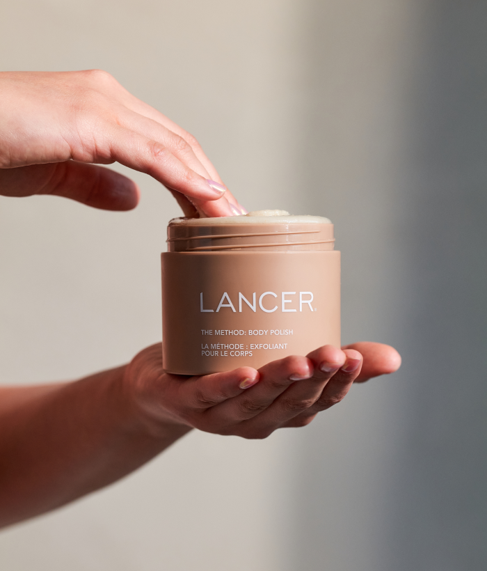Hand holding a Lancer skincare product jar against a neutral background-Lancer Skincare