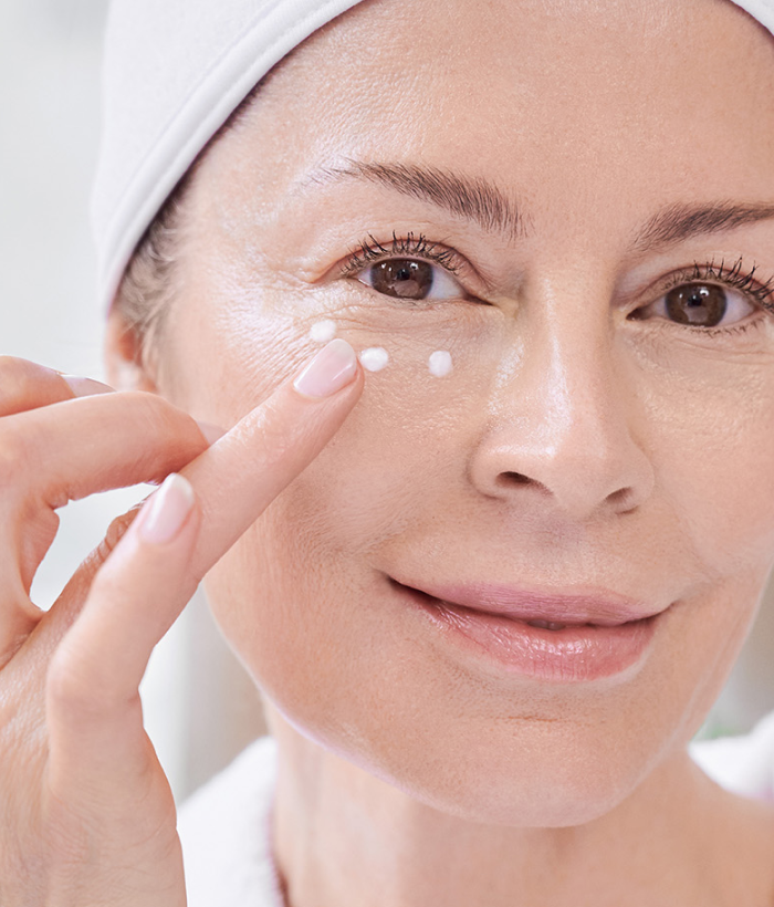 Woman applying cream to her face with a white towel on her head.-Lancer Skincare