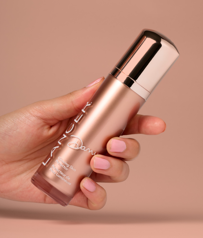 Hand holding a rose gold skincare bottle with a beige background-Lancer Skincare