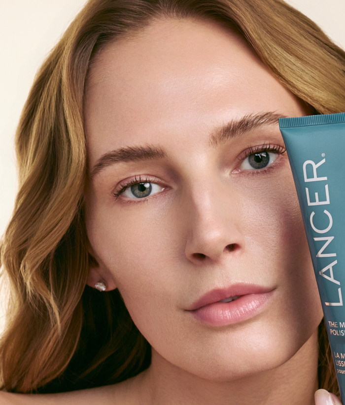 Woman holding a Lancer skincare product with a neutral background-Lancer Skincare