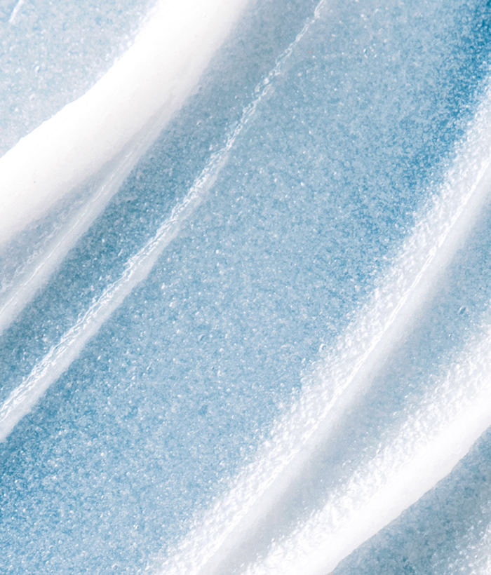 Close-up of white face exfoliator on a blue background