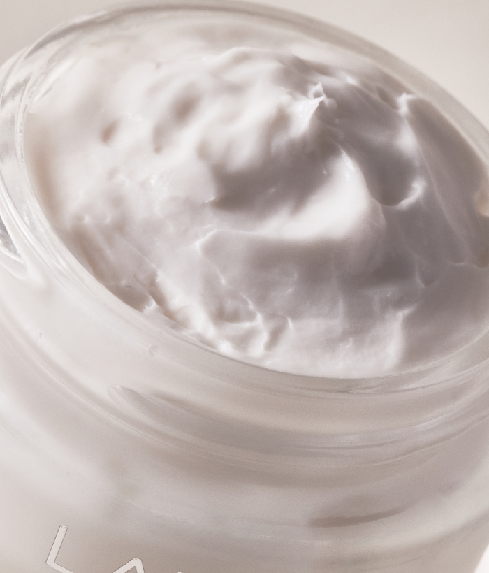 Close-up of a white cream in a jar with a visible brand logo.